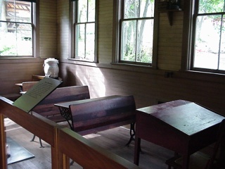 A shot of the one room school house teacher station and student desks. Brian questions the ergonomic appropriateness for healthy computer use.