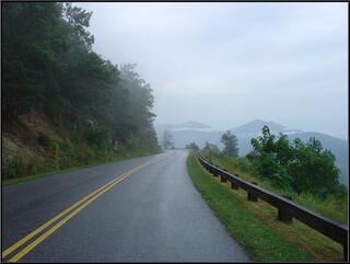 Mist rises up the hillside and over the road