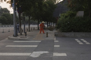 City worker sweeping the morning sidewalk with a huge homemade broom