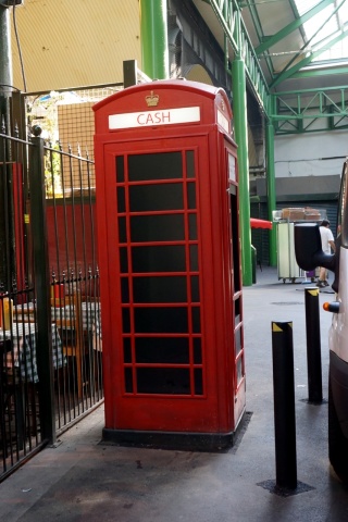 Red phone box repurposed as a cash machine under Borough Market