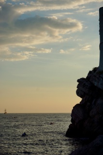 The gold cliff and a tall ship out past the swimmers.