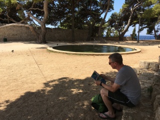 She reads by the pond while he takes the picture.