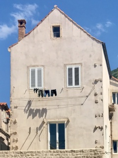 Laundry hung out to dry on a wall full of windows.