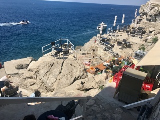 Buža Bar from above: a hole in the wall, a drink, and the sea.