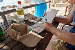 She paints the coast; I hold the beer.