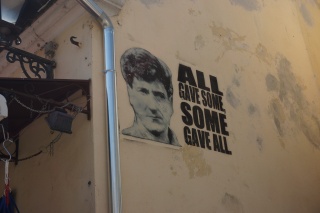 ALL GAVE SOME, SOME GAVE ALL, stenciled in a doorway.